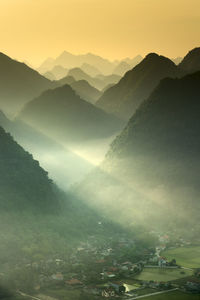 Scenic view of silhouette mountains during sunrise