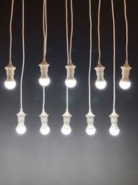 Close-up of illuminated light bulbs hanging against wall