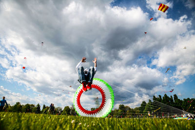 Man performing somersault by parachute against sky
