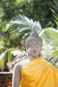 Old buddha statue against trees at wat yai chai mongkhon