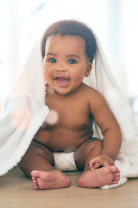 Portrait of shirtless baby boy lying on bed at home