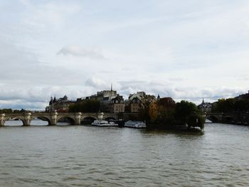 Arch bridge over river against sky in city