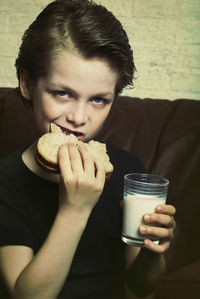 Portrait of boy eating breakfast while sitting on sofa at home