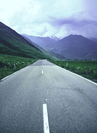 Road leading towards mountains against sky
