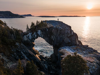 Man hiking at berry head arch at sunrise, along the east coast trail of newfoundland, canada