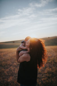 Close-up of mother carrying daughter against sky