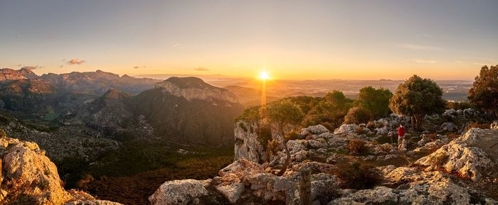 Panoramic view of rocks and mountains against sky during sunset