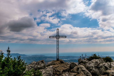 Cross on rock against sky