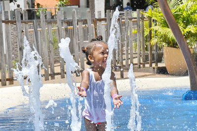 Happy girl playing with fountain at water park