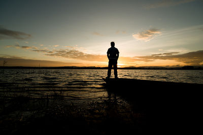 Full length of man standing at beach against sky during sunset