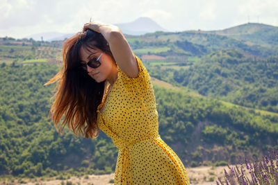 Beautiful woman standing on landscape against mountains