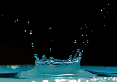 Droplets falling on rippled water against black background