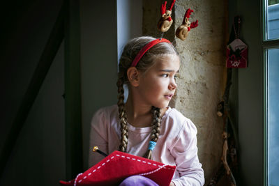 Girl in fun hat writes letter for santa and dreamily waits for gifts on christmas. winter holidays