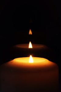 Close-up of lit candle in dark room