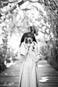 Portrait of woman standing against tree