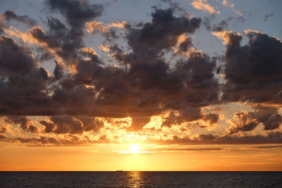 Scenic view of sea against dramatic sky during sunset