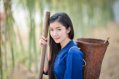 Young woman wearing traditional clothing while holding basket in bamboo grove