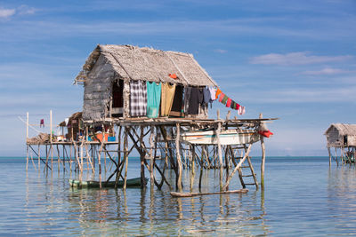 Traditional house on sea by building against sky