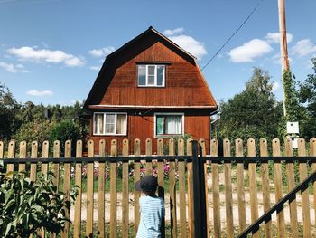 Rear view of woman by building against sky