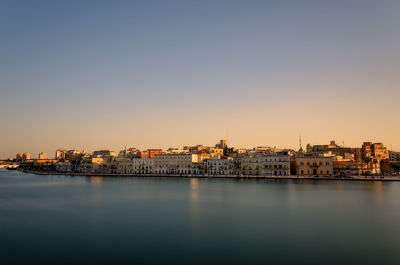 City by river against clear sky at dusk