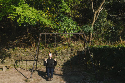 Woman standing on tree trunk in forest