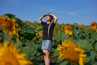 Full length of woman standing by sunflower against sky
