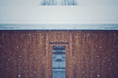 Window on wooden wall during snow fall