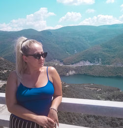 Young woman wearing sunglasses on mountain against sky