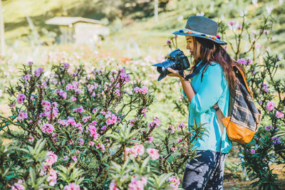 Side view of woman standing by flowering plants