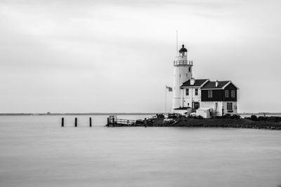 Lighthouse by sea against sky