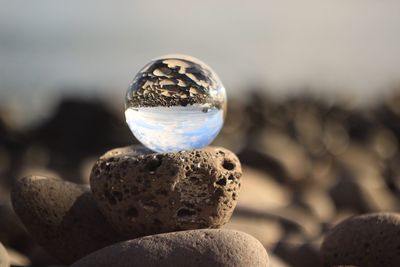 Close-up of crystal ball on pebble at beach