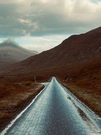 Empty road by mountain against sky