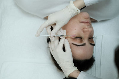 Cosmetologist applying eye mesotherapy to female patient