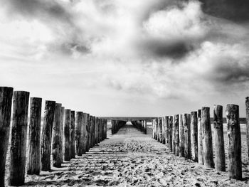 Wooden posts on beach against sky