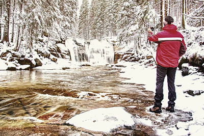 Rear view of woman standing against waterfall