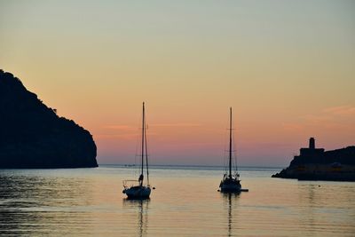 Silhouette sailboats in sea against sky during sunset