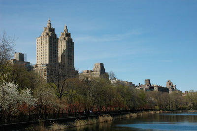 Buildings by river against sky in city