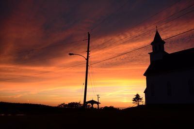 Low angle view of silhouette building against orange sky