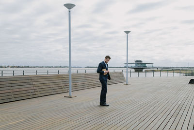 Full length of businessman standing on pier at sea