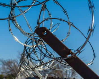 Low angle view of barbed wire on cable against sky