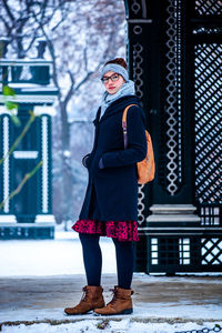 Full length portrait of woman with hands in pockets standing in snow