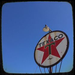 Low angle view of sign board against clear blue sky