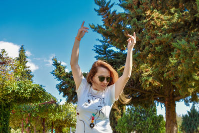 Woman with arms raised against trees