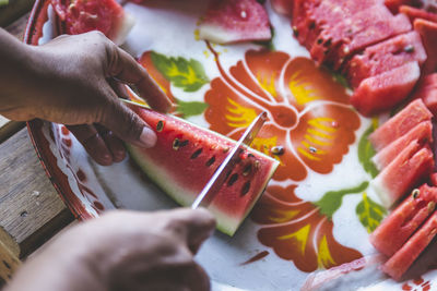 Close-up of man cutting watermelon slices on table