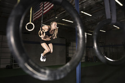 Female athlete exercising on gymnastic rings at health club