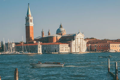 View of buildings by sea against clear sky