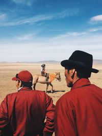 Rear view of people in desert against sky