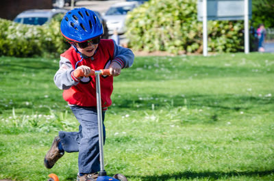 Cute boy riding push scooter at park