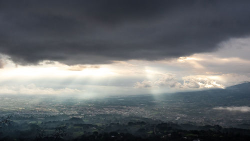 Sunlight streaming through clouds over landscape