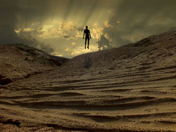 Full length of man levitating on sand at beach against sky